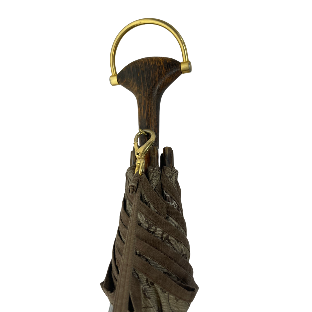 Ombrello in tessuto beige con logo gucci, manico in legno con staffa oro, tracolla staccabile.
